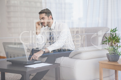 Businessman working on his couch seen through glass