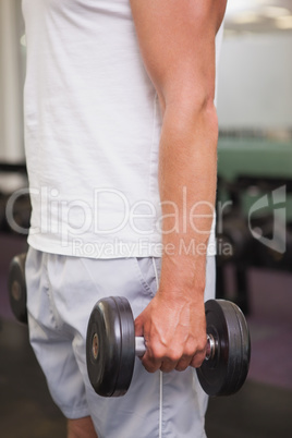 Fit man lifting heavy black dumbbell