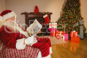 Santa claus reading newspaper on the couch