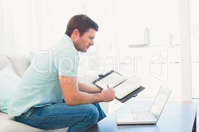 focused man on a laptop with a notebook