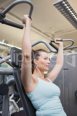 Fit brunette using weights machine for arms