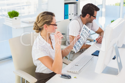 Blonde editor looking over contact sheet at her desk