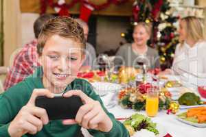 Young boy holding smartphone during christmas dinner
