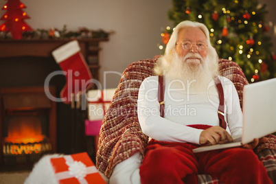 Smiling santa claus typing on laptop