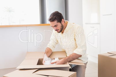 Young man unpacking boxes in kitchen