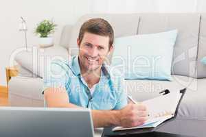 Smiling man writing on a notebook