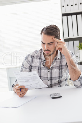 Casual businessman readnig document at his desk