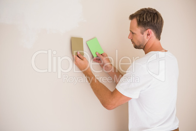 Handsome decorator sanding down the wall