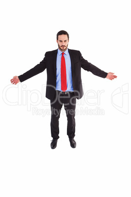 Unsmiling businessman standing with arms outstretched