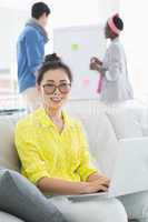 Young creative woman using laptop on couch