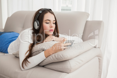 Pretty brunette listening to music on the couch