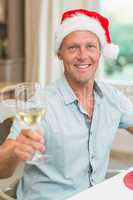 Handsome man in santa hat toasting with white wine
