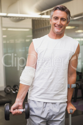 Injured man holding dumbbell in the weights room