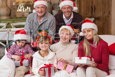 Portrait of a happy extended family in santa hat holding gifts