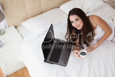 Pretty brunette using laptop on bed