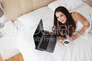 Pretty brunette using laptop on bed