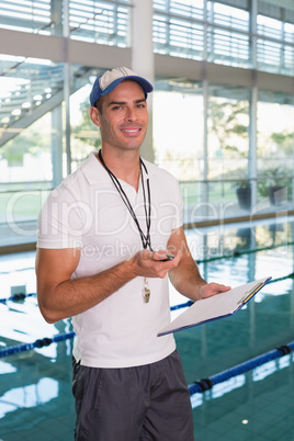 Swimming coach with stopwatch by pool at leisure center