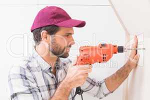 Construction worker drilling hole in wall