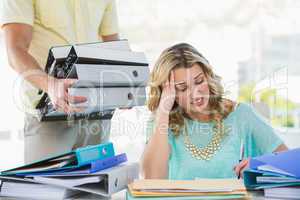 Stressed creative businesswoman with stack of files