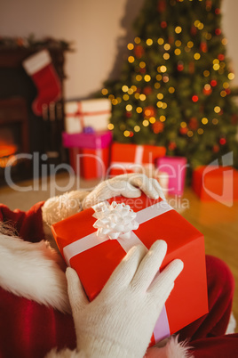 Santa claus holding a red gift with a white bow