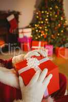 Santa claus holding a red gift with a white bow