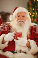 Happy santa claus holding a red mug