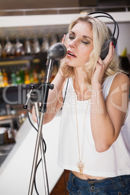 Pretty blonde with headphone singing into microphone