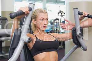 Fit young woman using fitness machine at gym