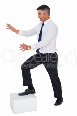 Businessman with one foot on a cube and arms out