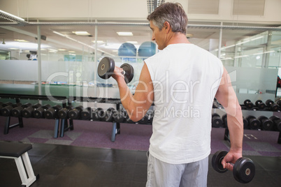 Fit man lifting heavy black dumbbell