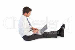 Businessman sitting on the floor typing on his laptop