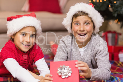 Surprised brother and in santa hat sister opening a gift