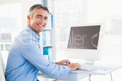 Smiling man typing on keyboard and looking at camera