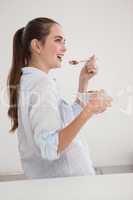 Pretty brunette eating bowl of cereal