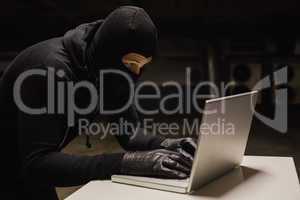 Robber at desk hacking a laptop