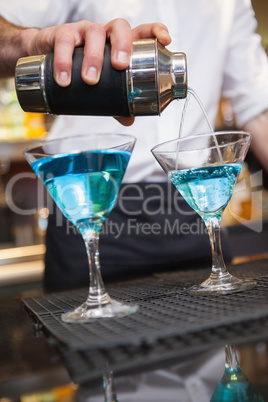 Bartender pouring cocktail into glasses