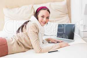 Pretty brunette using laptop on bed