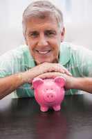 Smiling mature man with piggy bank