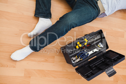 Mid section of a man lying with tools box