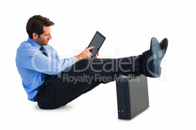 Businessman sitting on the floor with feet up on suitcase