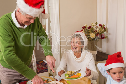 Grandfather in santa hat serving roast turkey at christmas