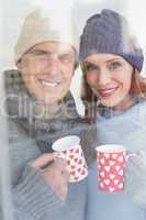 Happy couple in warm clothing holding mugs