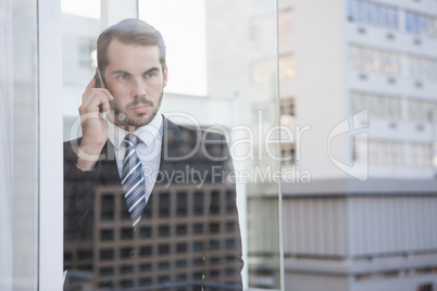 Businessman looking out window on the phone