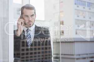 Businessman looking out window on the phone