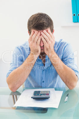 Stressed businessman covering his face at his desk