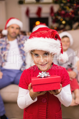 Smiling daughter holding gift in front of her family