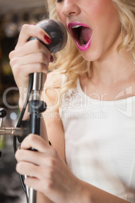 Close up of beautiful blonde singing into a microphone