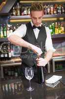 Handsome waiter opening a bottle of red wine