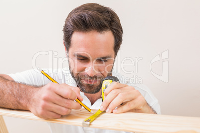 Casual man measuring plank of wood