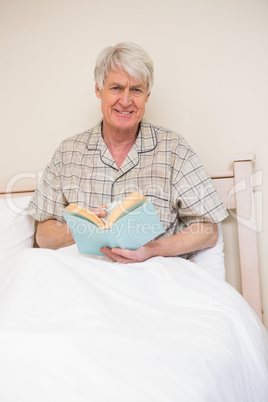 Senior man reading a book in bed